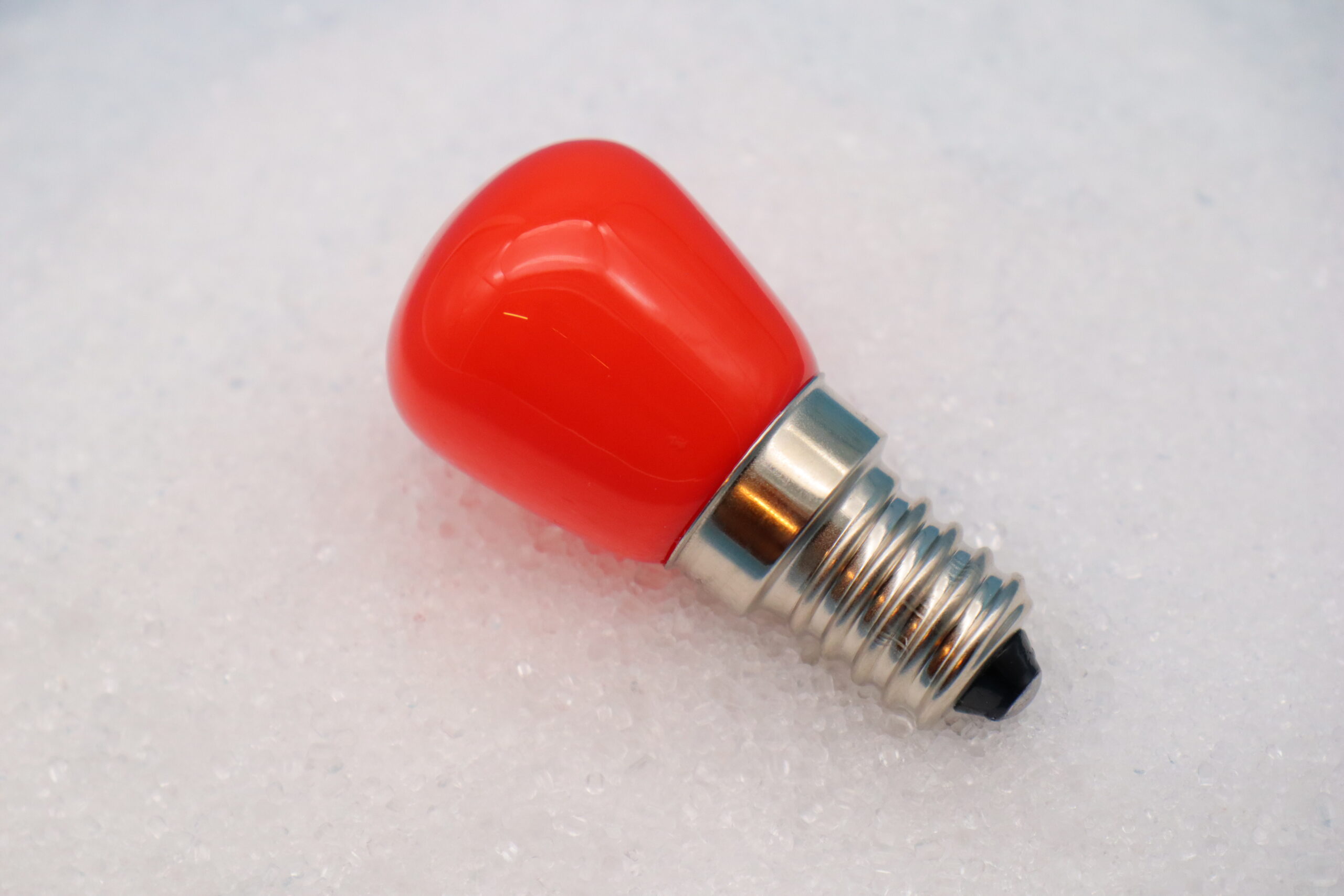 Glühbirne E14 (LED) „Orange“ Glühbirne auf Häufchen aus Salz liegend in Nahaufnahme